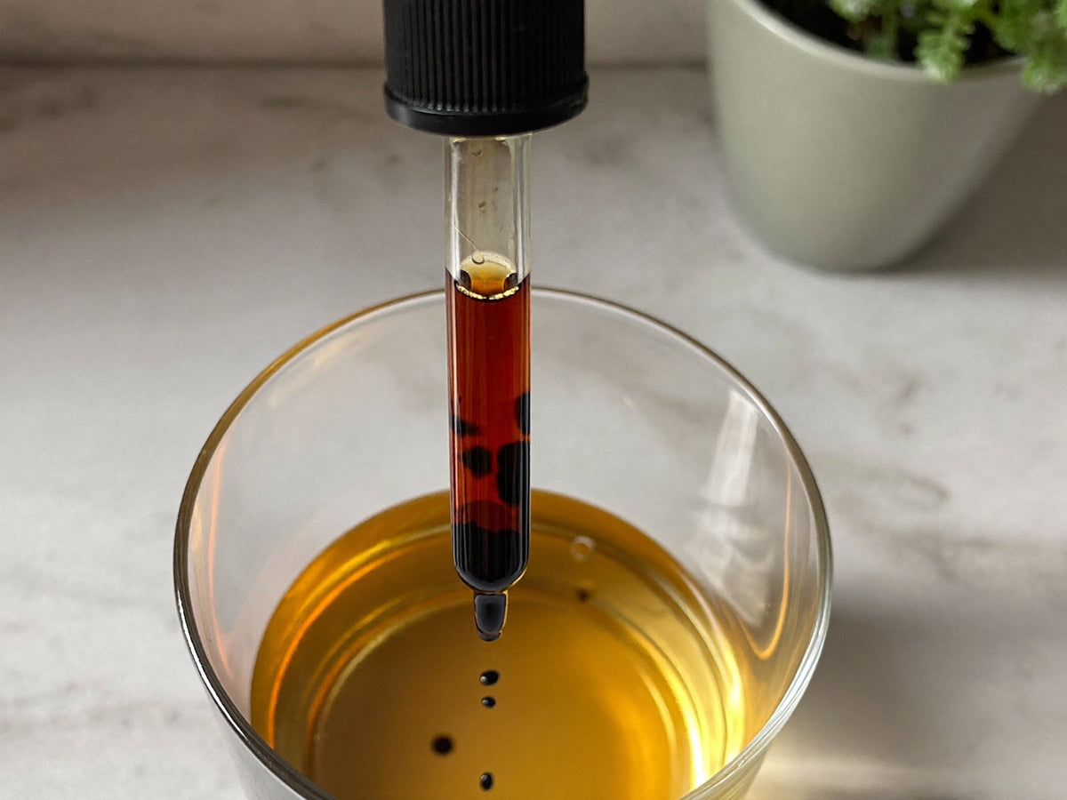 A dark plant concentrate dropped into a glass of water Image